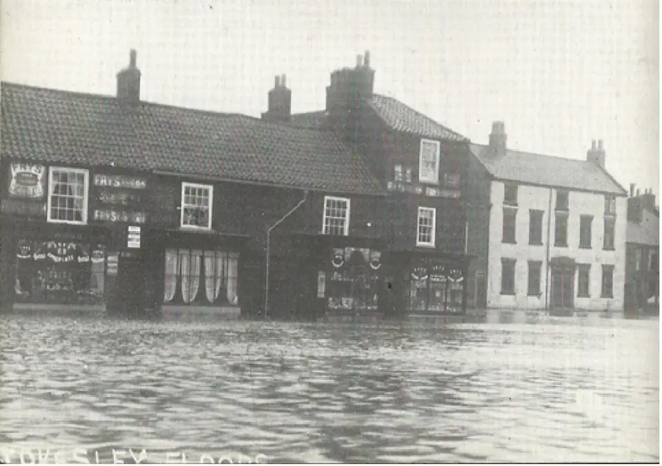 Old photograph of a row of houses with the street in front of them under floodwater.